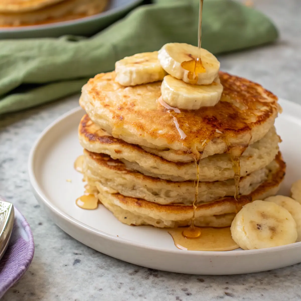 Fluffy banana cottage cheese pancakes stacked with banana slices and syrup