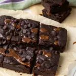 Fudgy cottage cheese protein brownies cut into squares with melted chocolate chips on parchment