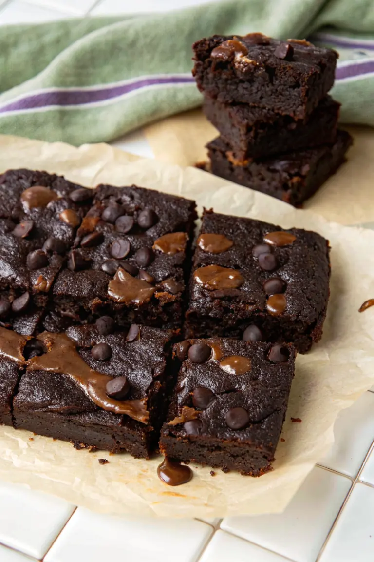 Fudgy cottage cheese protein brownies cut into squares with melted chocolate chips on parchment
